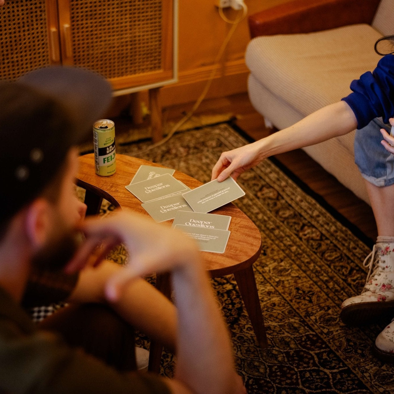 People playing Deeper Questions conversation card game seated around a small wooden table